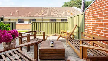 A patio area with wooden furniture, a table, and a bench.