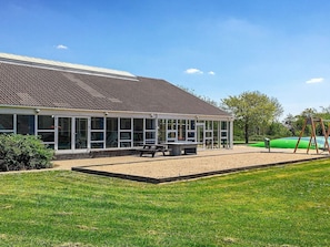 A building with a tiled roof, large windows, and a grassy area with a bench and swing set. - 6 Person Holiday Park Home in Hemmet (Hemmet)