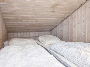 Ein kleines Zimmer mit einem Einzelbett, Holzwänden und einer schrägen Decke.