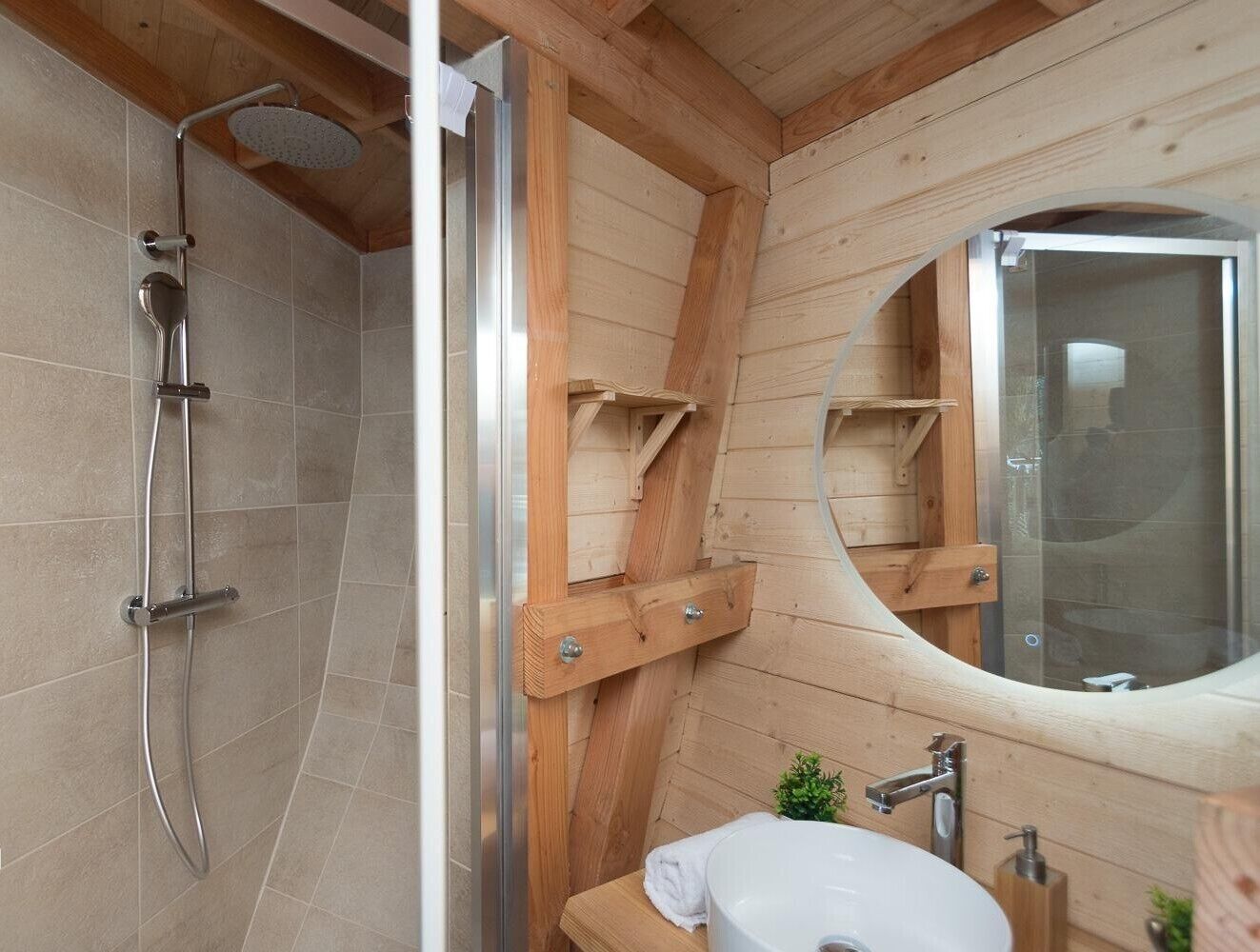 Ein Badezimmer aus Holz mit Dusche, Waschbecken und Spiegel.