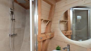 Ein Badezimmer aus Holz mit Dusche, Waschbecken und Spiegel.