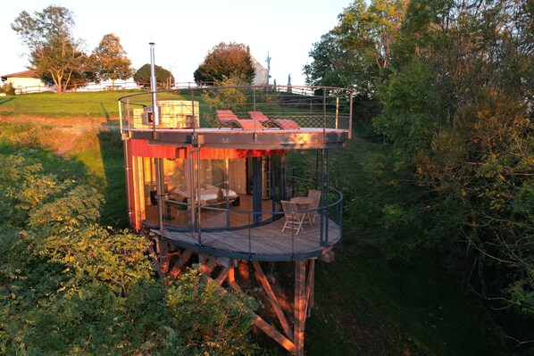 A wooden tower with a glass enclosure, furnished with a bed, a table, and chairs. - Domaine des Étoiles - Logements insolites (Gillonnay)