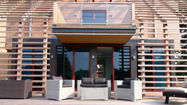 A modern house with a flat roof, large glass doors, and outdoor furniture. - Luxurioeses Chalet in Wendorf (Kuhlen-Wendorf)