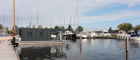 A marina with docked boats, a small building with a sloped roof, and calm water.