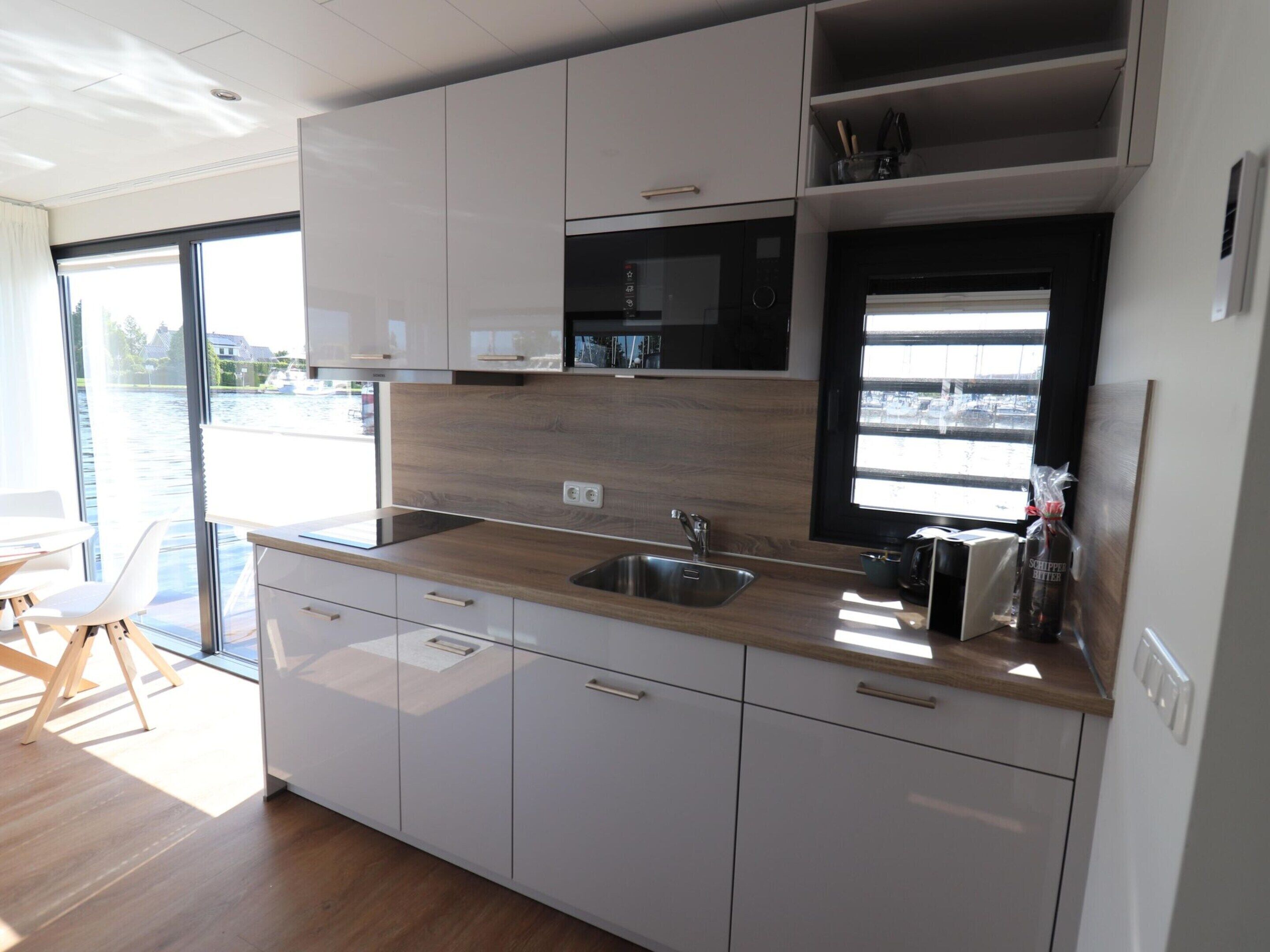 Eine moderne Küche mit weißen Schränken, einer Holz Arbeitsplatte und einer eingebauten Mikrowelle.