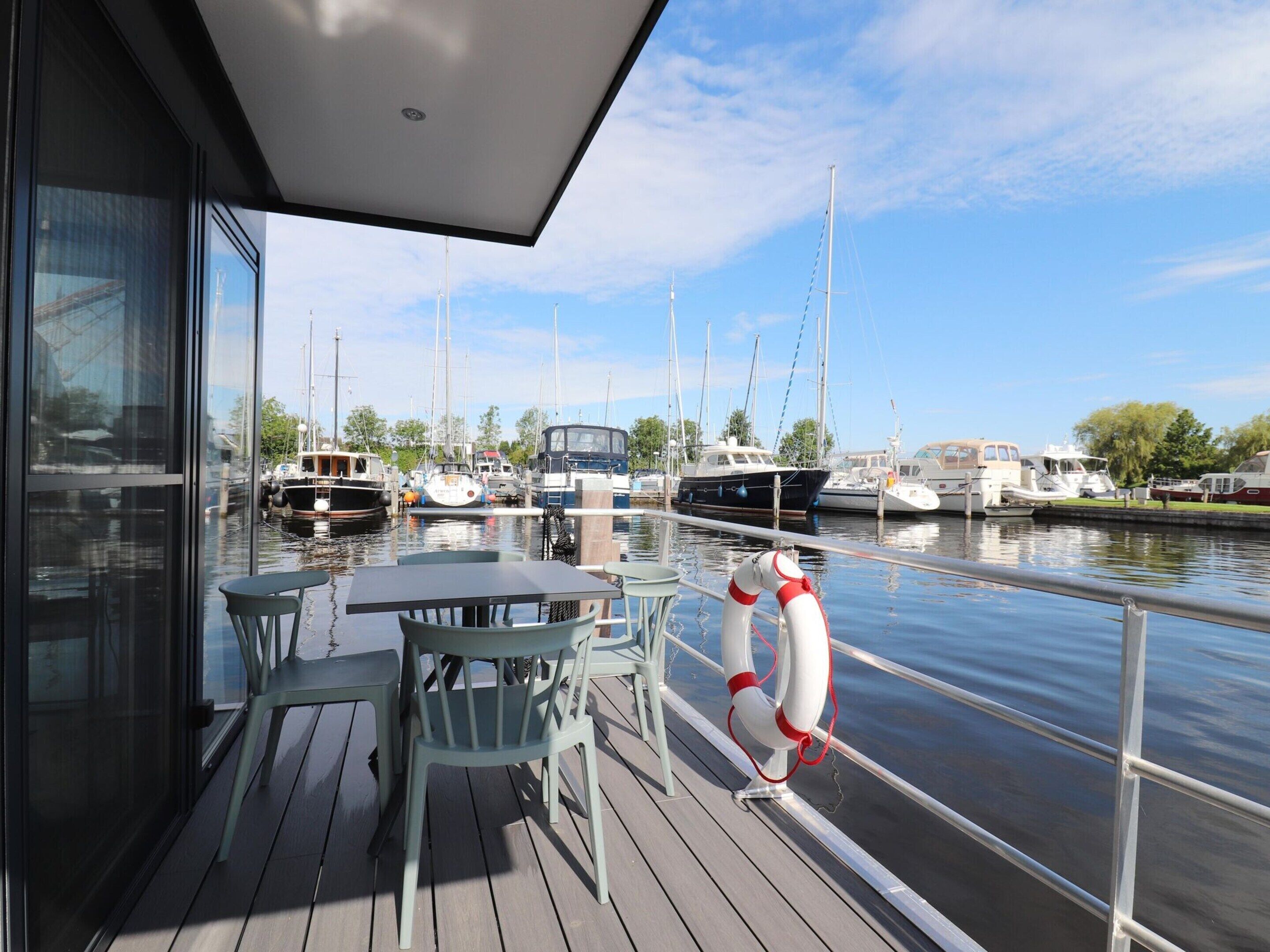 A deck with outdoor seating overlooking a marina with various boats.