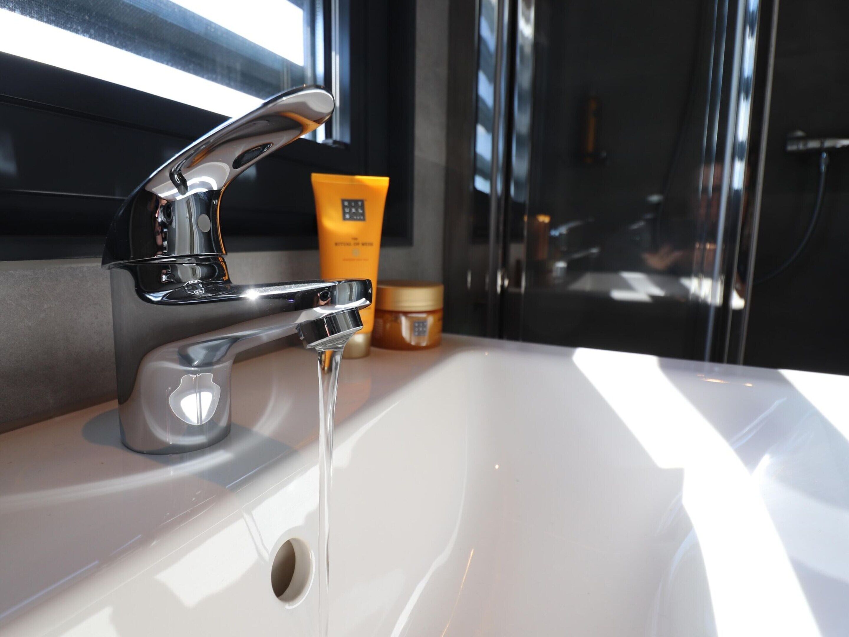 Un lavabo de salle de bain avec un robinet chromé et une fenêtre en arrière-plan.