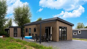 Una moderna area patio esterna con piscina, posti a sedere e una struttura in legno.