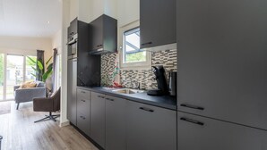 Una cucina moderna con mobili scuri, una macchina da caffè nera e una finestra che si affaccia all'esterno.