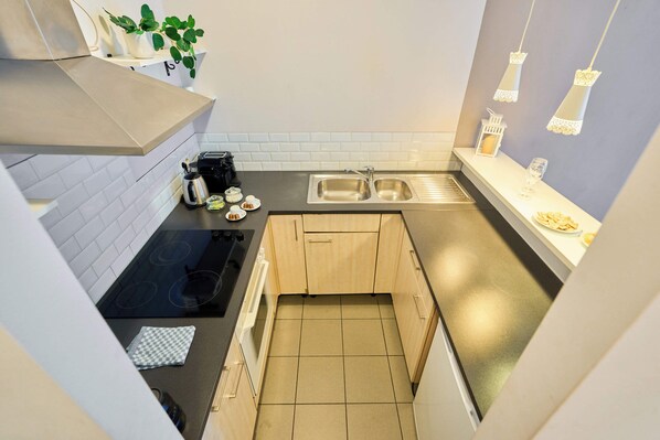 Una cocina moderna con estufa negra, pileta de acero inoxidable y alacenas de madera.