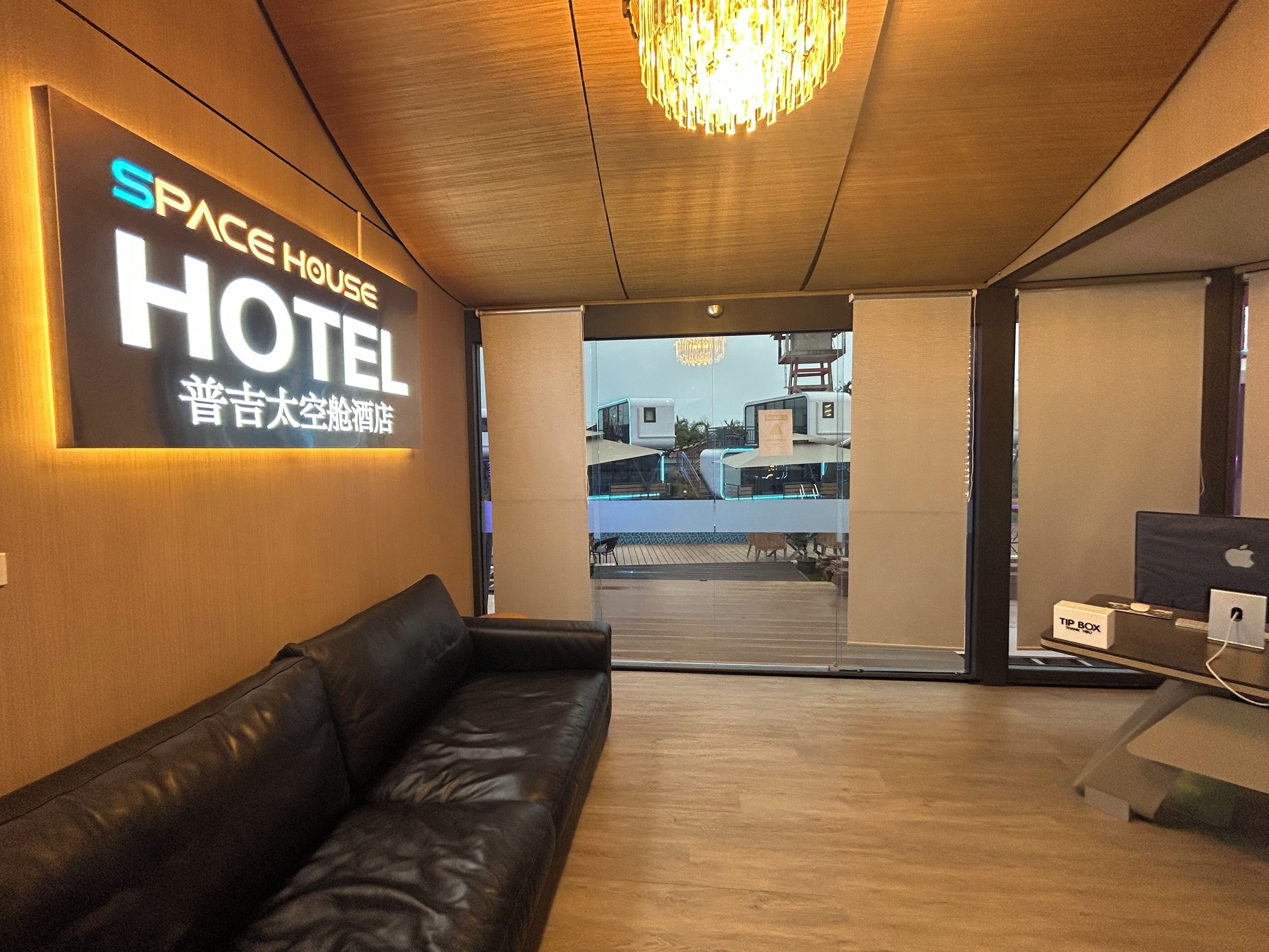 A hotel lobby with a leather sofa, a chandelier, and a sign reading "SPACE HOUSE HOTEL".