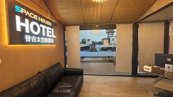 A hotel lobby with a leather sofa, a chandelier, and a sign reading "SPACE HOUSE HOTEL".