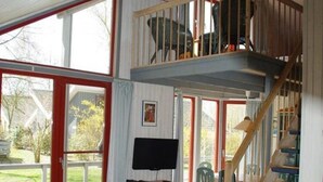 Une pièce dotée d’une grande fenêtre, d’un téléviseur et d’un escalier menant à un niveau supérieur.