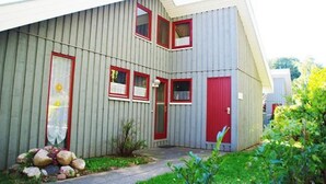 Un bâtiment à deux étages, à l’extérieur gris, avec des touches de rouge sur les fenêtres et les portes.