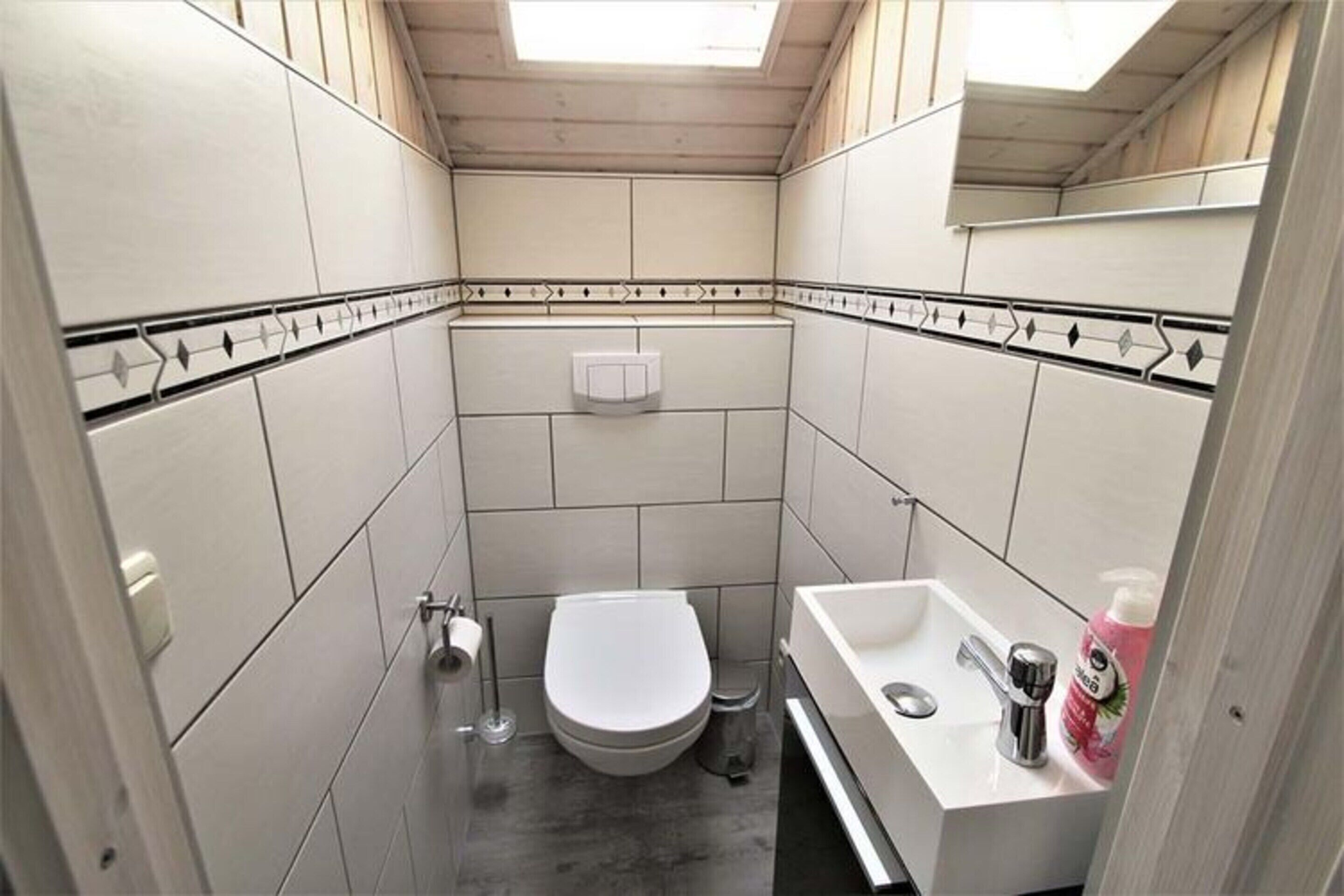 Pieni, käytännöllinen kylpyhuone, jossa on wc, pesuallas ja peili.