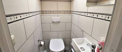 A small, compact bathroom with a toilet, sink, and a mirror.