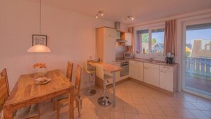 Une cuisine compacte avec un coin repas, un luminaire suspendu et une vue sur l’extérieur par une fenêtre.