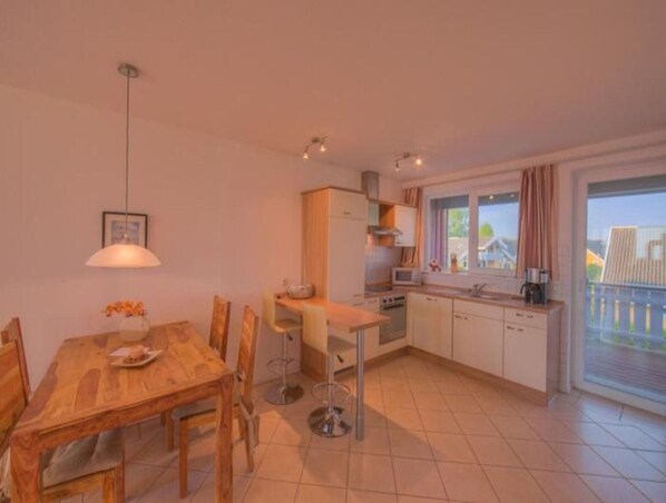 Une cuisine compacte avec un coin repas, un luminaire suspendu et une vue sur l’extérieur par une fenêtre.