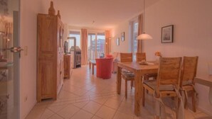 Un grand espace de vie comprenant une table à manger, des chaises, une poubelle rouge et une cheminée.
