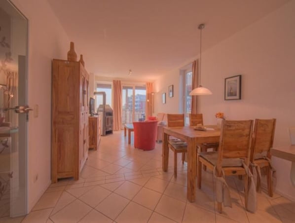 Un grand espace de vie comprenant une table à manger, des chaises, une poubelle rouge et une cheminée.