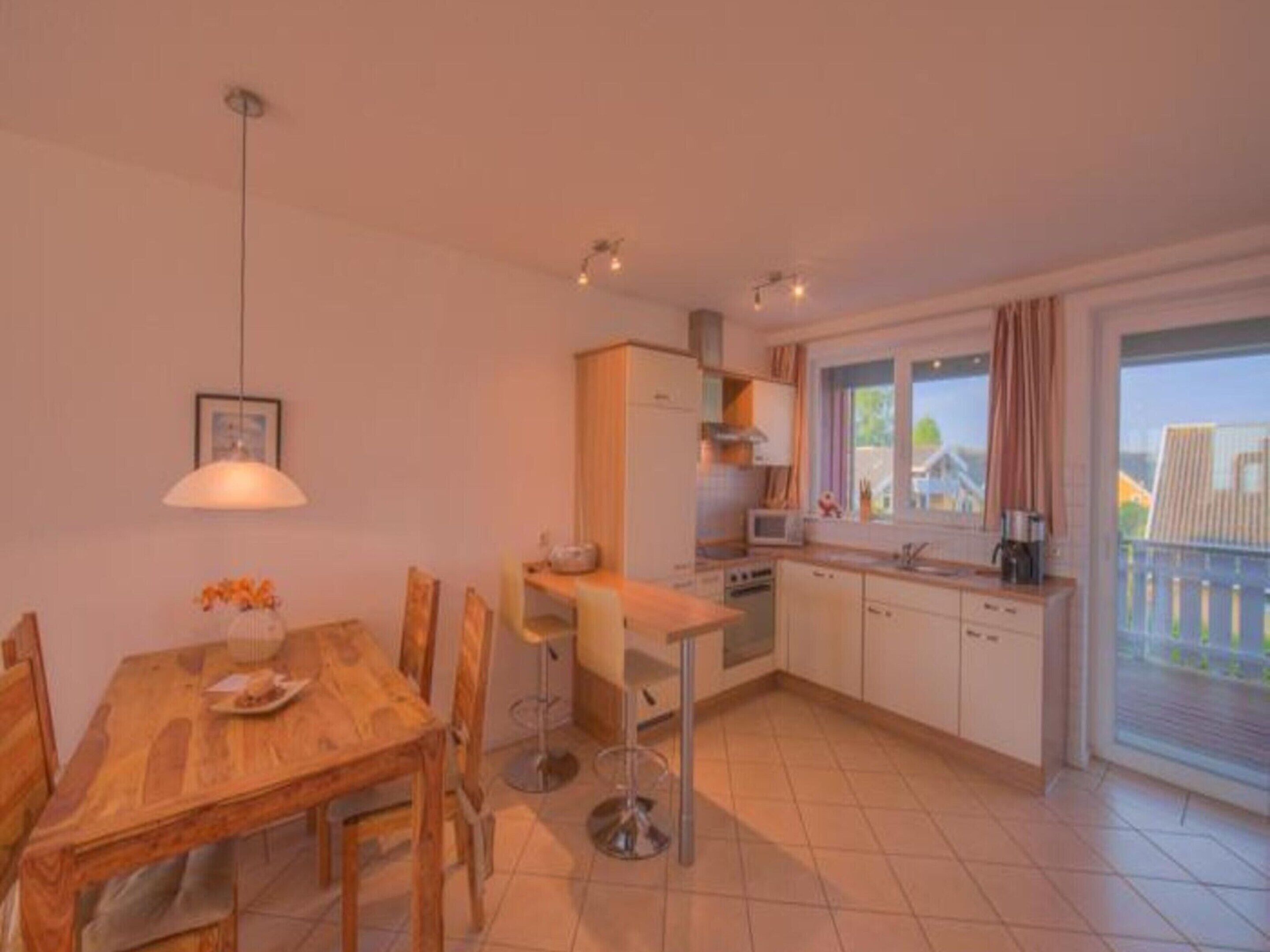 A compact kitchen with a dining area, a window with curtains, and a view of the outside.