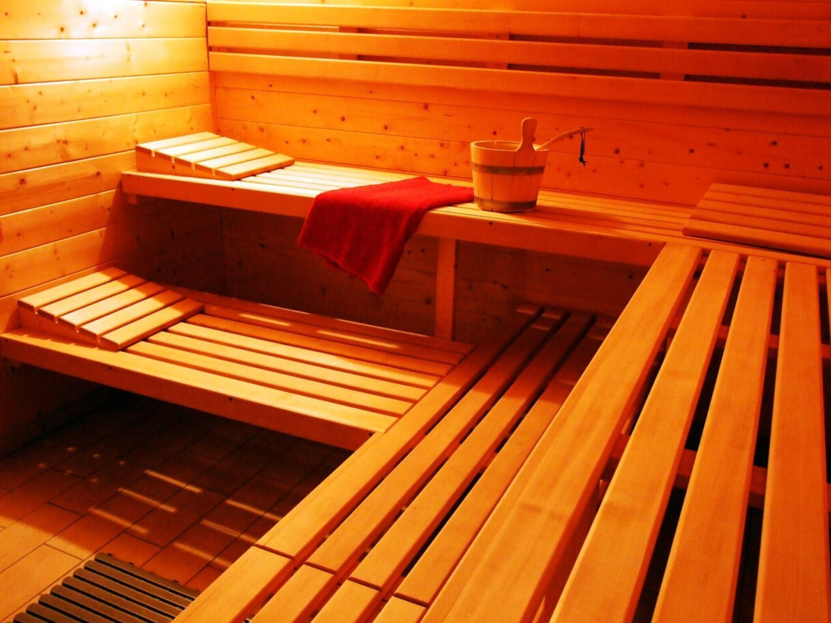 Eine Sauna mit Holzbänken und einer Bank mit Handtuch in Rot.
