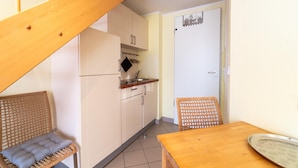 A compact kitchen with a wooden staircase, a dining table, and a wicker chair. - Elegant Eingerichtete Ferienwohnung (Mirow)