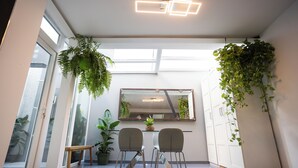 A modern interior with a dining area, large windows, and indoor plants. - Villa Naim Guest House Cala del Moral (Rincon de la Victoria)