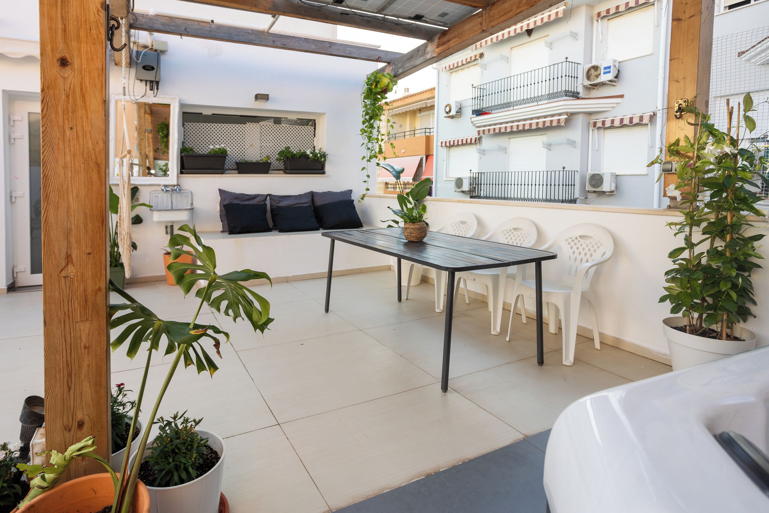 A patio with a table and chairs, potted plants, and a white car.