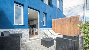 A modern outdoor seating area with wicker furniture and a stone floor.