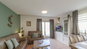 Una sala de estar con sofá, mesa de centro, televisor y aparador.