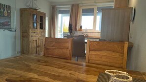 A compact kitchen with wooden cabinets, a dining table, and a view of the outdoors through a window. - Appartement im Ferienpark in Rechlin (Rechlin)