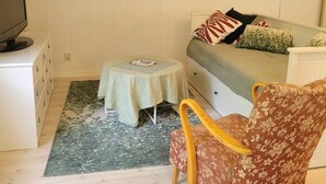 A small, cozy room with a bed, a chair, a table, and a television.