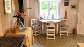 A dining area with a table and chairs, a stove, and a window with a view of greenery.