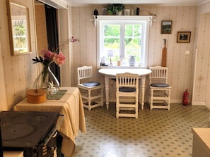 A dining area with a table and chairs, a stove, and a window with a view of greenery. - 6 Person Holiday Home in Bergsjo (Bergsjo)