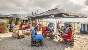 Un área de estar al aire libre con muebles de madera y sombrillas, con vista a una playa.