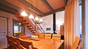 Une table à manger en bois, quatre chaises, un lustre et un escalier.