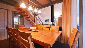 Una mesa de madera para comer con cuatro sillas, una araña y una escalera.