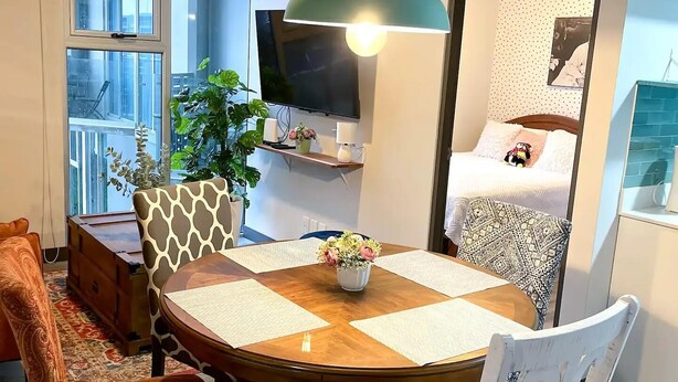 Een eetruimte met een ronde houten tafel, witte stoelen en een groene hanglamp.