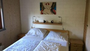 Un dormitorio con dos camas individuales, cabecero de madera, repisa con adornos y una obra de arte en la pared.
