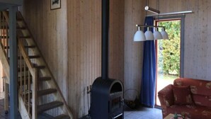 Un interior de madera con estufa de leña, una escalera y un sofá rojo.