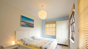 A bedroom with a bed, bedside table, wardrobe, and a painting on the wall. - Ferienhaus, Fedderwardersiel (Butjadingen)