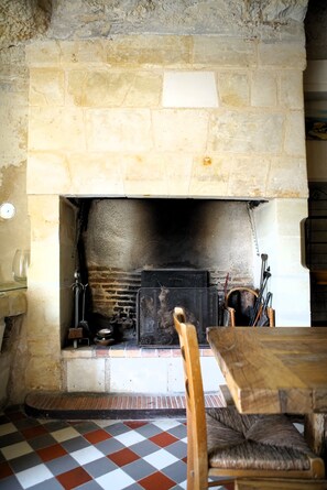 Cozy gathering space with a traditional fireplace, wooden table, and cushioned bench.