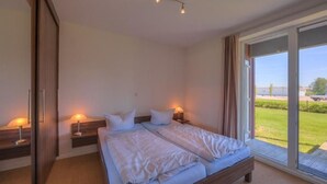 Un dormitorio con dos camas, una puerta corredera y vistas al exterior.