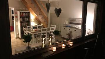 A dining area with a table and chairs, a bookshelf, and a staircase.