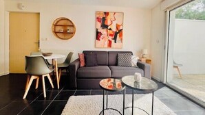 A modern living room with a sofa, a coffee table, and a dining area. - T2 with terrace near Les Minimes (La Rochelle)