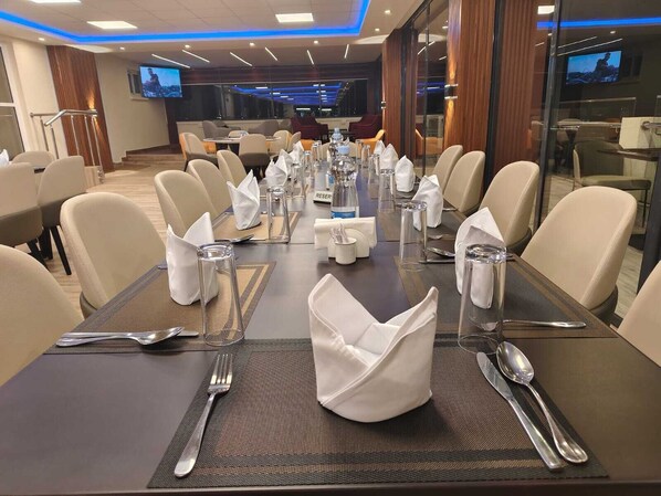 A conference room with a long table set for a meeting, equipped with nameplates, water glasses, and a television screen displaying a landscape. - Glam Hotel Nairobi, Near Westgate Mall, Westlands (Nairobi)