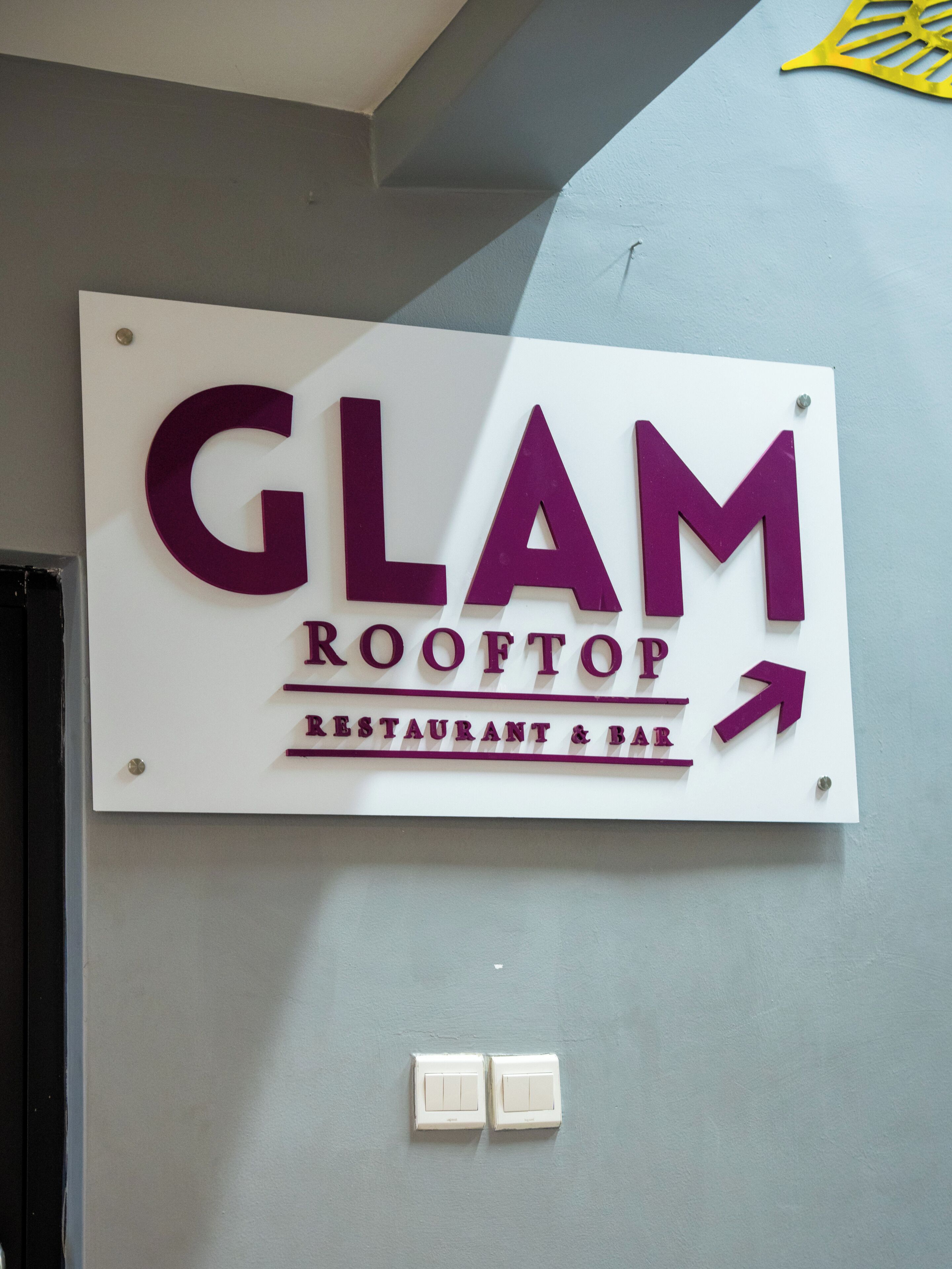 A sign for 'GLAM ROOFTOP RESTAURANT & BAR' with an arrow pointing to the right.