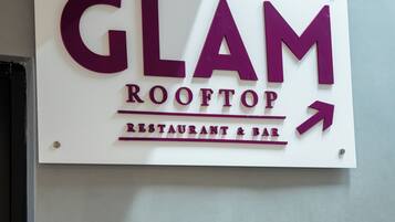 A sign for 'GLAM ROOFTOP RESTAURANT & BAR' with an arrow pointing to the right.