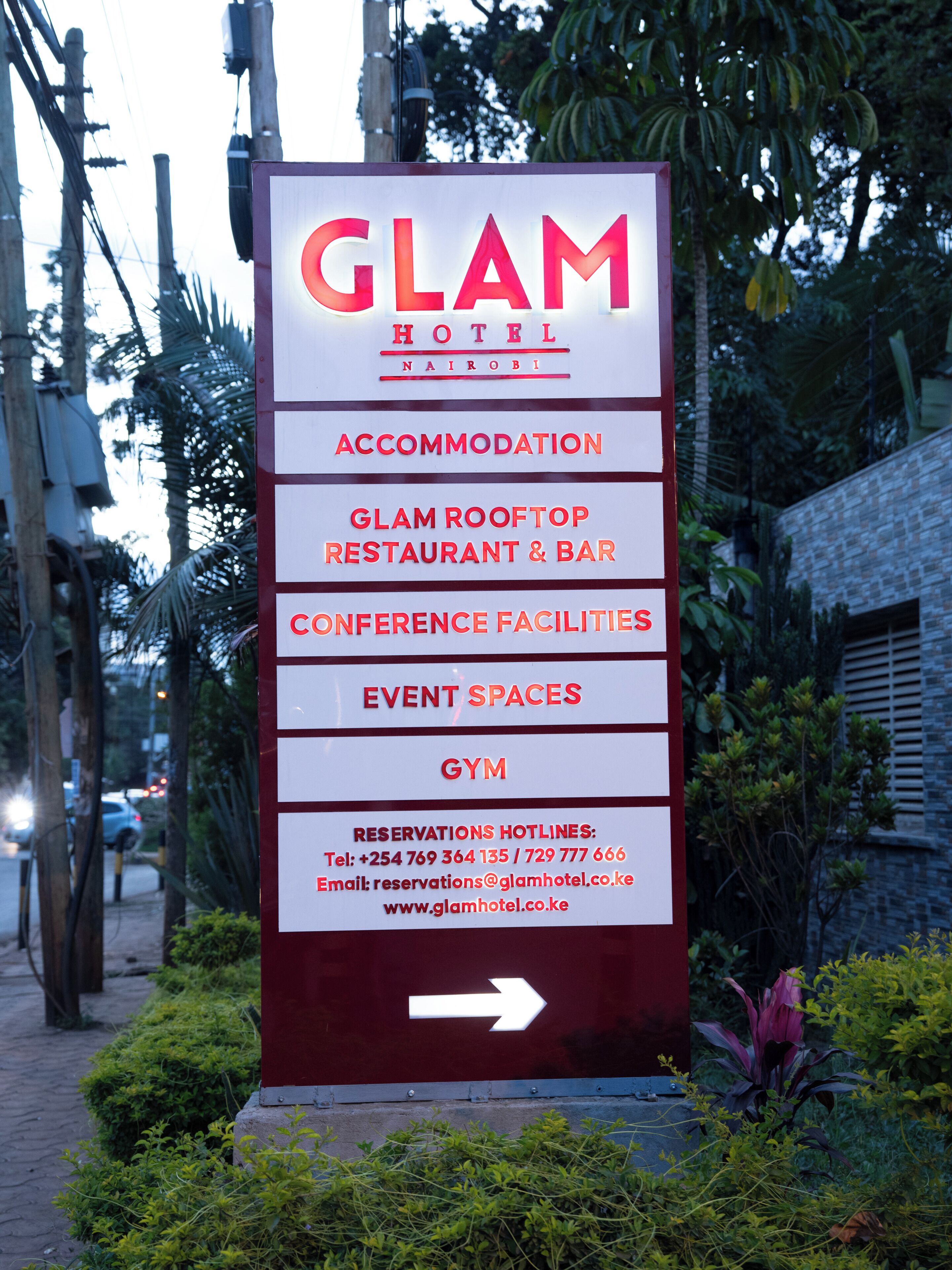 A sign for the Glam Hotel in Nairobi, listing amenities such as accommodation, a rooftop restaurant and bar, conference facilities, event spaces, and a gym.